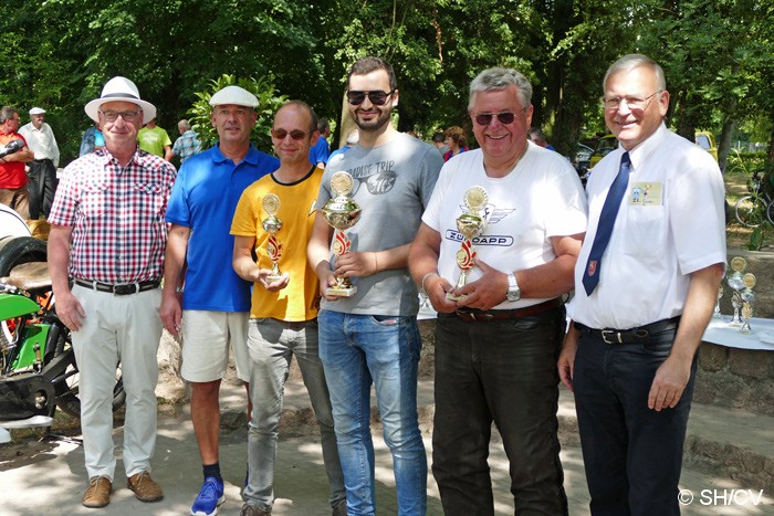 Bild: Siegerehrung im Gutspark in Mößlitz. Prämiert wurden die Gewinner der Fahrzeugklassen M1 bis M4 (Motorräder) und A1 bis A5 (Automobile). Desweiteren gab es Pokale für das Schönste Motorrad & Automobil sowie für das Schönste Kostüm und der Pechvogel.
Sie Siegerehrung nahm Fahrtleiter Ralf Zschoche, Ortsbürgermeister Jürgen Ebinger sowie Stadtbürgermeister Rolf Sonnenberger vor.